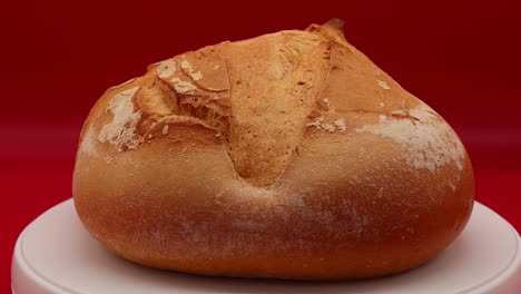 Frischer-Laib-Apulisches-Brot,-Pane-Pugliese,-Rotierend-Auf-Rotem-Hintergrund