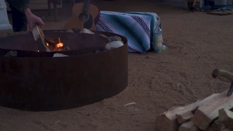 un hombre lanza otro tronco al fuego en el desierto