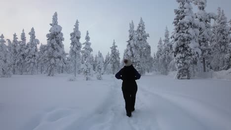 girl exploring winter scenery in snowy forest in lapland, finland, arctic circle