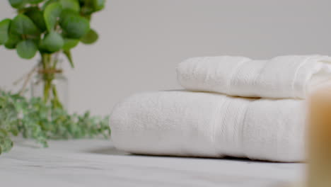 person picking up towels at relaxing spa day with lit candles with green leaved plant