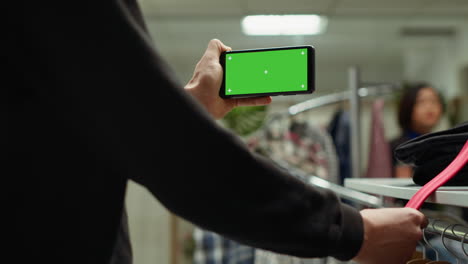 persona sosteniendo una tableta con pantalla verde en una tienda de ropa