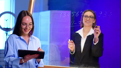 pros working together modernly. two professionals engage in a discussion while one writes on a glass board in a contemporary office setting