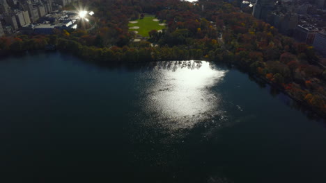 Aerial-view-of-water-reservoir-and-autumn-colour-trees-in-Central-Park-surrounded-by-town-development.-Manhattan,-New-York-City,-USA