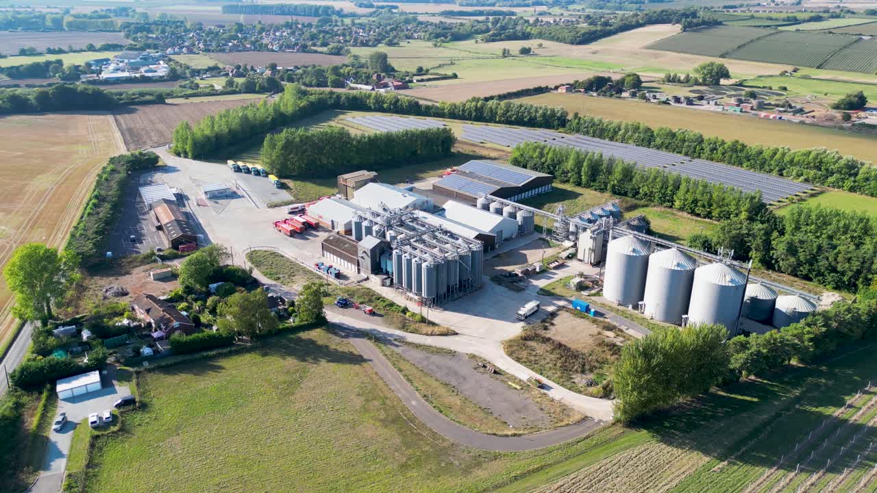 Rückwärts-Dollyfahrt, Weitwinkelansicht einer Industrieanlage mit Silos auf dem Land