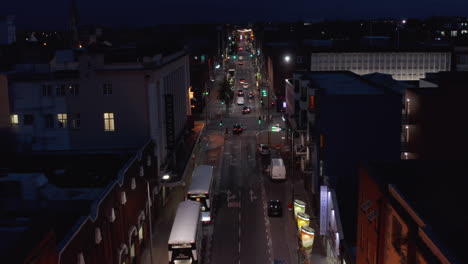 Seguimiento-Hacia-Adelante-De-Un-Grupo-De-Automóviles-Que-Conducen-En-Una-Calle-De-Sentido-único-En-La-Ciudad-Nocturna.-Camino-Bordeado-Por-Vehículos-Estacionados-Y-Casas-Adosadas.-Limerick,-Irlanda