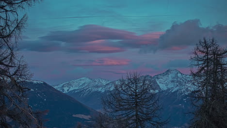Short-time-lapse-of-pink-sunset-clouds-above-snow-capped-mountains-at-dusk