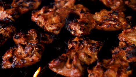 flame broiled barbecue chicken sizzling and grilling on a gas grill - close up panning shot to the left