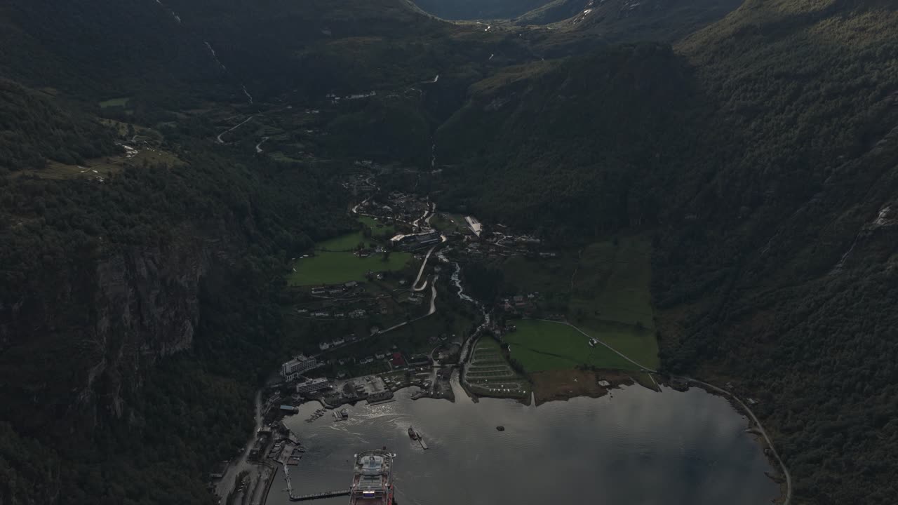 Arka planda karlı dağ zirvelerinin yükseldiği Geiranger köyü, havadan görünüm.