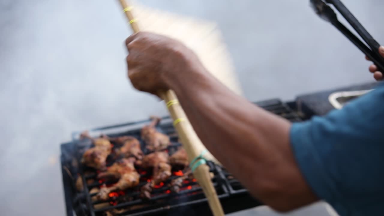 Ripresa al rallentatore di un venditore ambulante asiatico che cucina Ayam Bakar su una griglia fumante