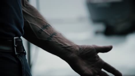 captivating close-up of hands showcasing intricate tattoos and veins in a dramatic coastal environment