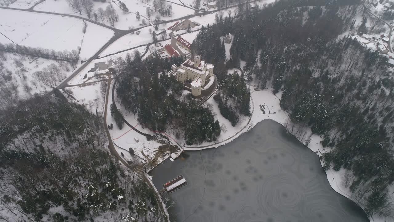 vista aérea del lago congelado y el castillo de cuento de hadas en la distancia en invierno