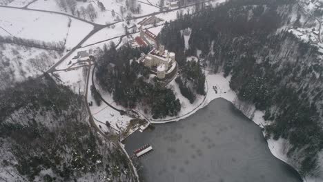 Vista-Aérea-Del-Lago-Congelado-Y-El-Castillo-De-Cuento-De-Hadas-En-La-Distancia-En-Invierno