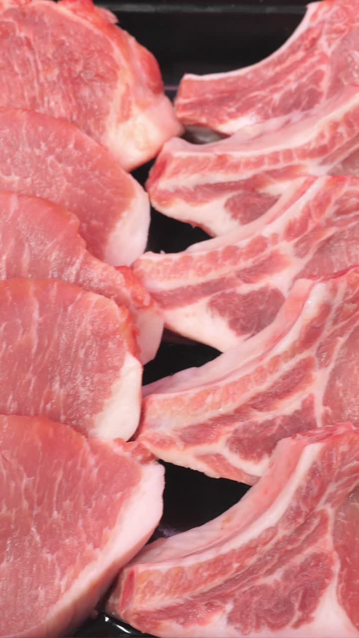 Freshly cut pork chops arranged neatly on a black tray, showcasing marbling and texture, ideal for culinary presentations and recipes