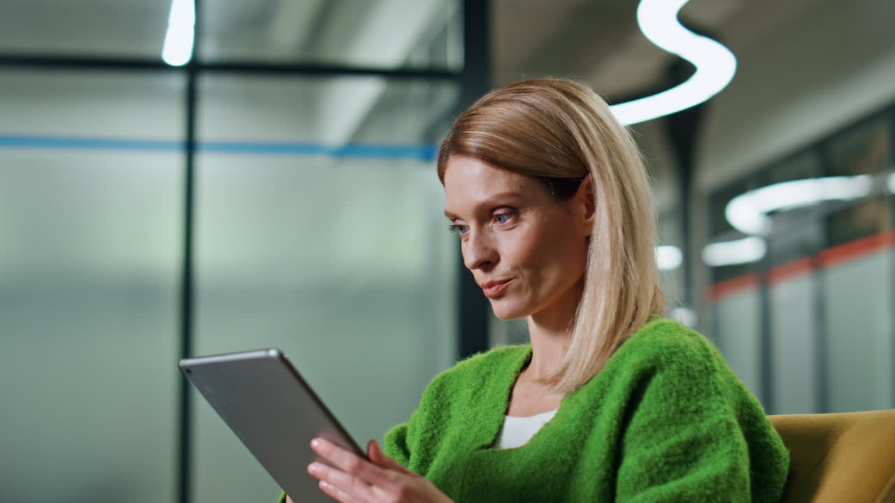 Smiling woman waving to partner at hall portrait. Positive woman watching tablet