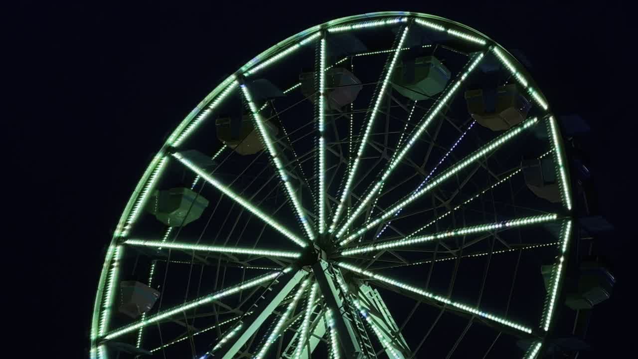 Grande roue avec des lumières LED en mouvement sur fond noir au crépuscule