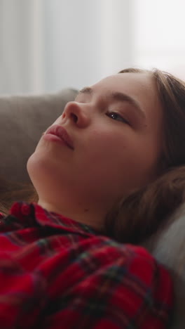 tired young woman in red checkered shirt falls down onto comfortable sofa with pillow closeup slow motion. resting after hard working day. lady at home