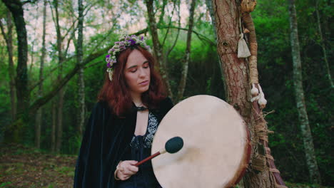 druid girl in a forest playing her shamanic drum high to low angle wide shot