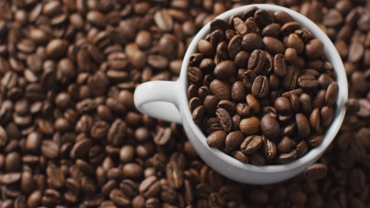 Video af kop med kaffebønner over ristede brune kaffebønner