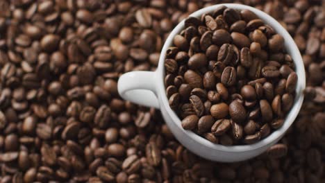 video of cup of coffee beans over roasted brown coffee beans