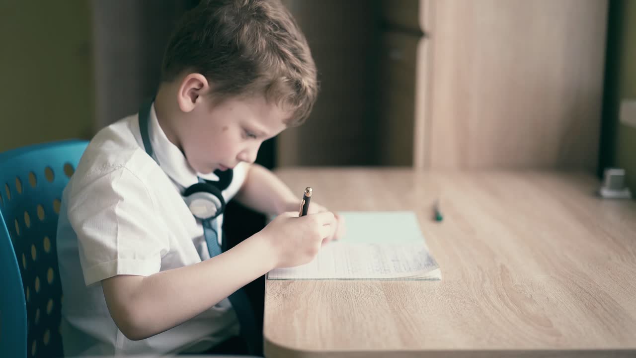 Bambino seduto con le cuffie che fa i compiti scolastici