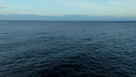 Dolly-Aéreo-Hacia-El-Mar-Con-Nubes-En-El-Horizonte,-Vibrante-Tono-Azul-Oscuro-En-Las-Corrientes-De-Agua