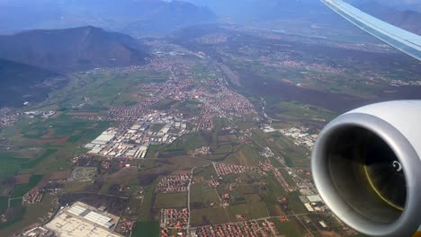 imágenes aéreas de un valle rodeado de montañas con un motor de avión en primer plano