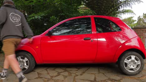 a shot of a person walking around a small red car