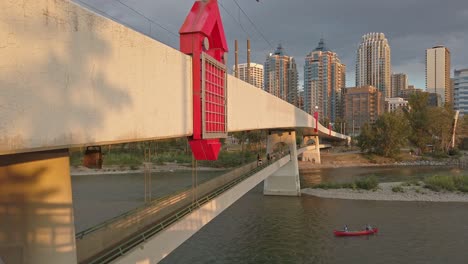 Red-canoe-on-Bow-river-in-city-under-the-bridge-sunset-Calgary-Alberta-Canada