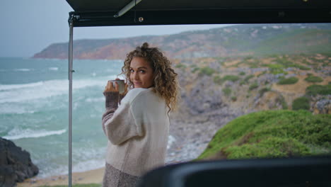 happy tourist looking ocean waves standing trailer terrace with coffee cup.