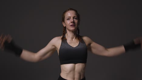 studio portrait of mature woman wearing gym fitness clothing resting and recovering after exercise