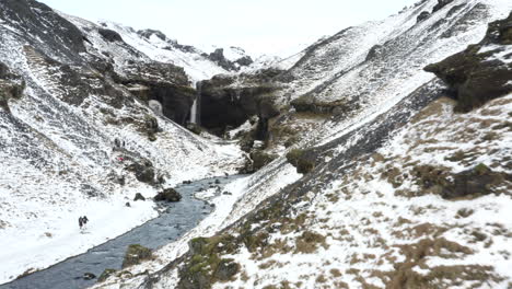 AERIAL:-Snow-Canyon-with-Horses-in-Iceland-Green-Grass,-Snow,-Ice