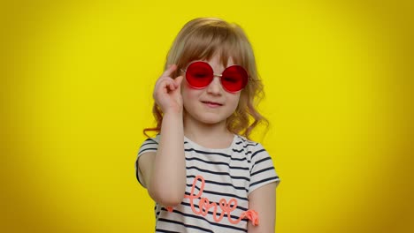 Happy-playful-kid-girl-in-sunglasses-blinking-eye,-looking-at-camera-with-smile,-winking,-flirting