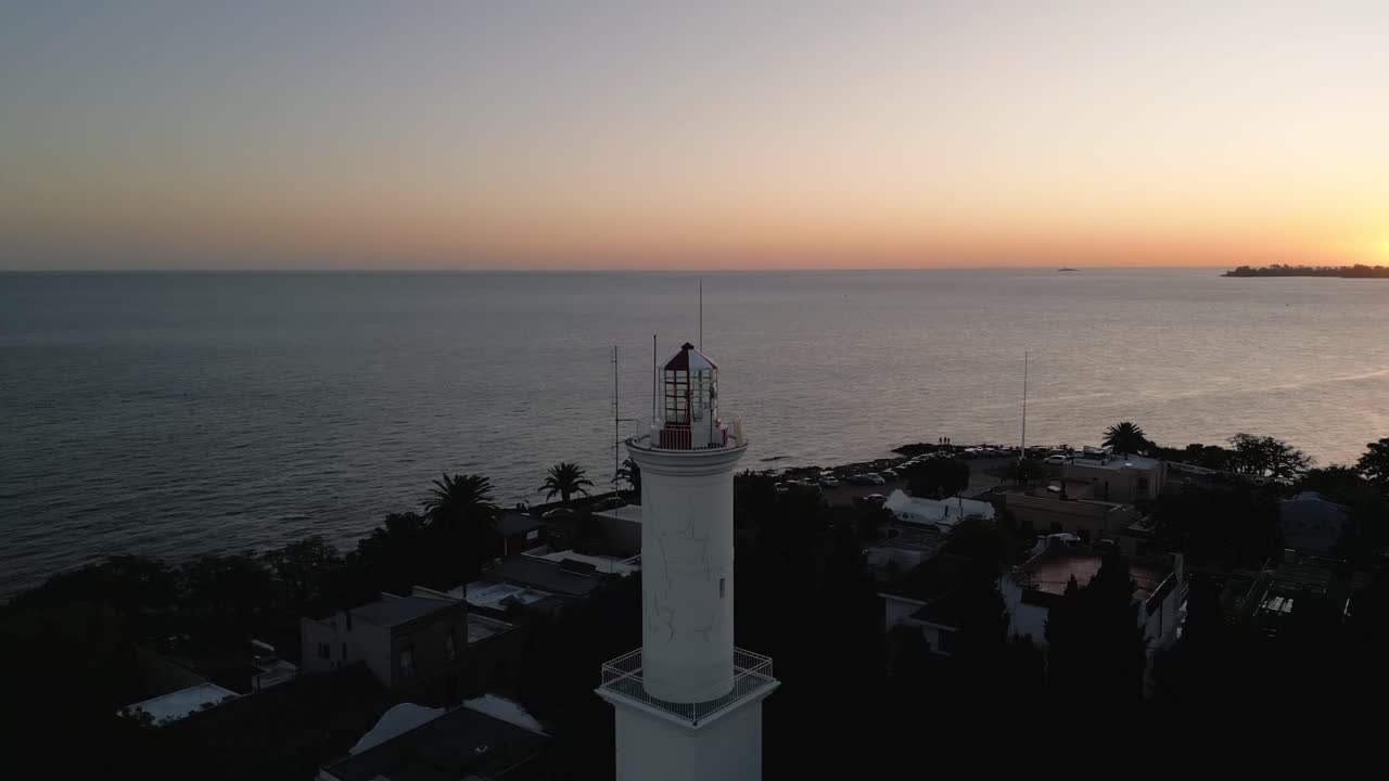 vista aérea orbitando la colonia del sacramento faro de la ciudad vieja con el resplandor del amanecer en el horizonte de uruguay