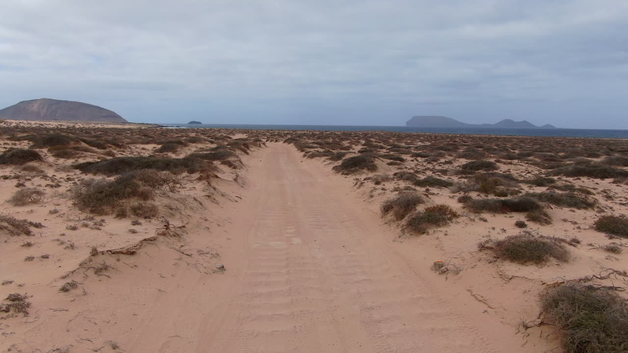 Point of view driving on a sandy road towards the ocean on the island of La Graciosa in Lanzarote, Canary Islands, Spain