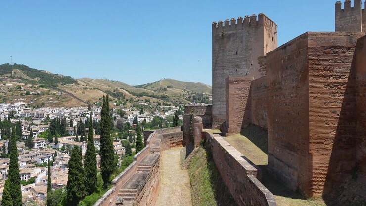 Mura difensive storiche e torre della fortezza dell'Alcazaba nel complesso dell'Alhambra che domina Granada e le colline circostanti dell'Andalusia, Spagna.