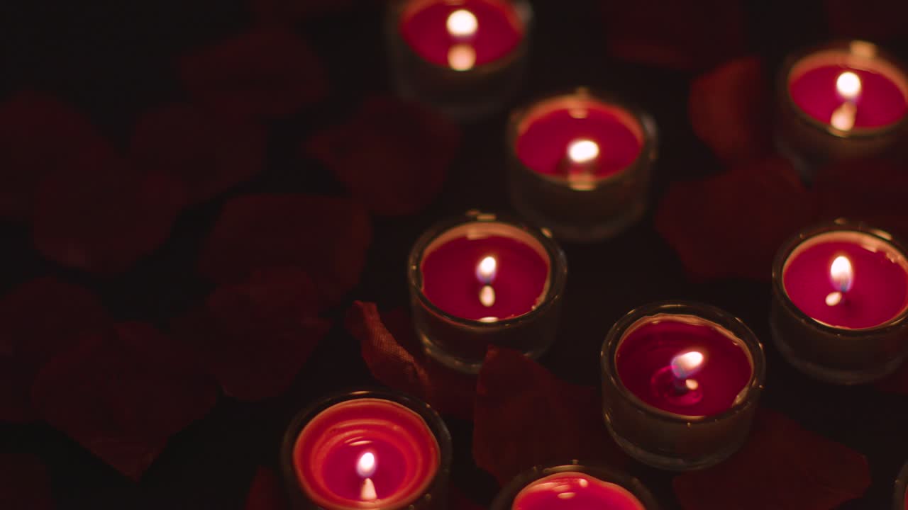 романтические красные свечи на фоне, покрытые лепестками роз.