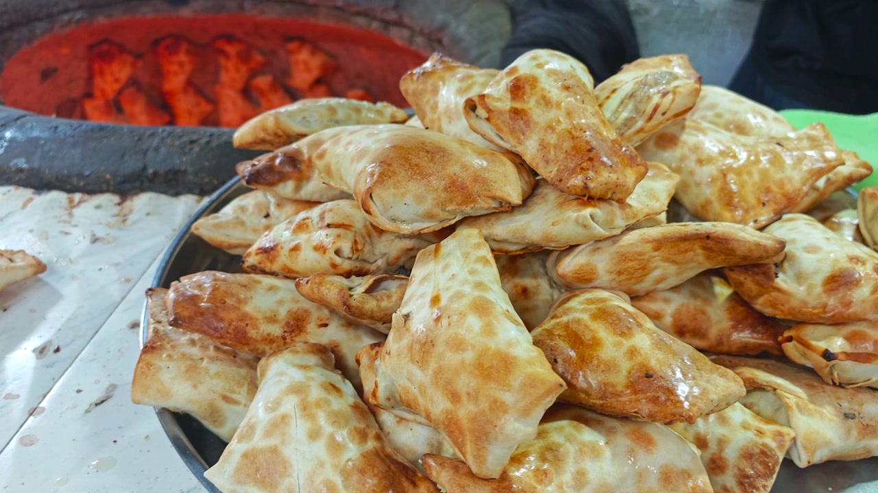 Samsa appena sfornati su un vassoio in un tradizionale forno tandoor.