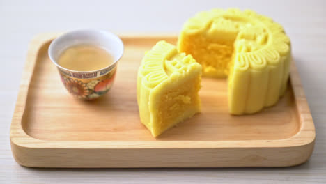 Chinese-moon-cake-custard-flavour-with-tea-on-wood-plate