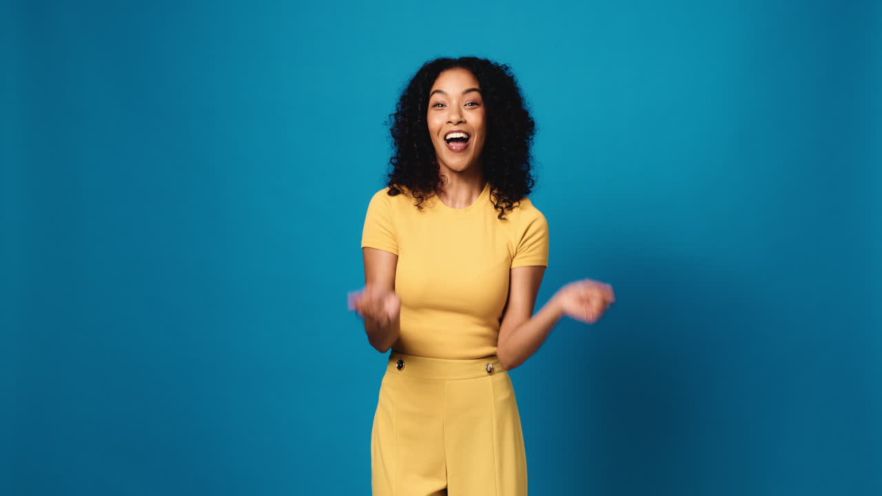 Excited Woman in Yellow Outfit Against Blue Background