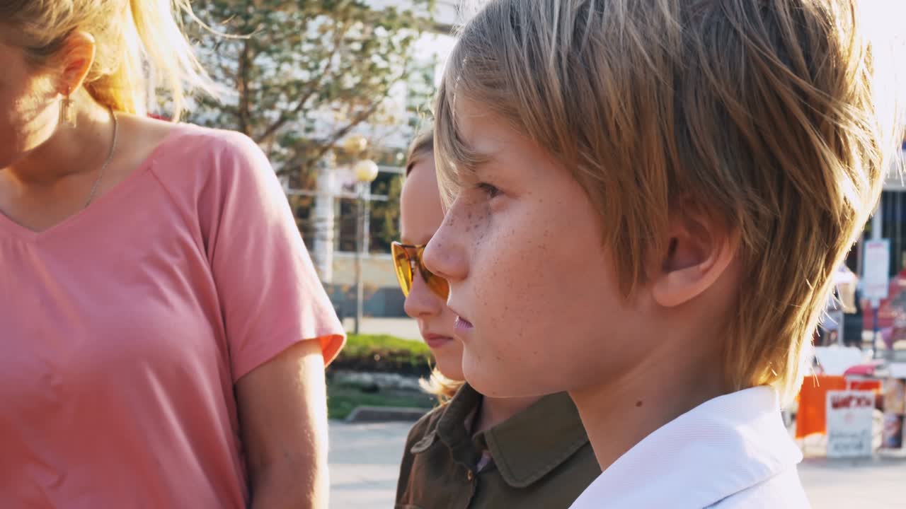 태양의 광선에 어머니와 함께 클로즈업 아이들, 은 머리 아이들, 노란 안경을 입은 여동생