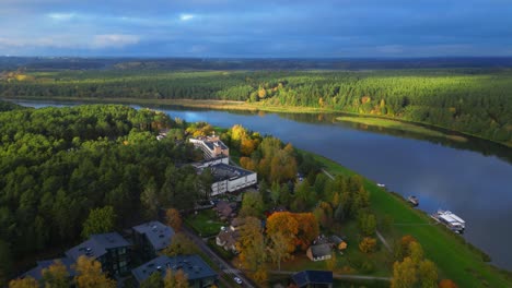 drone forward revealing egles sanatorium next to river in lithuanian panoramic landscape