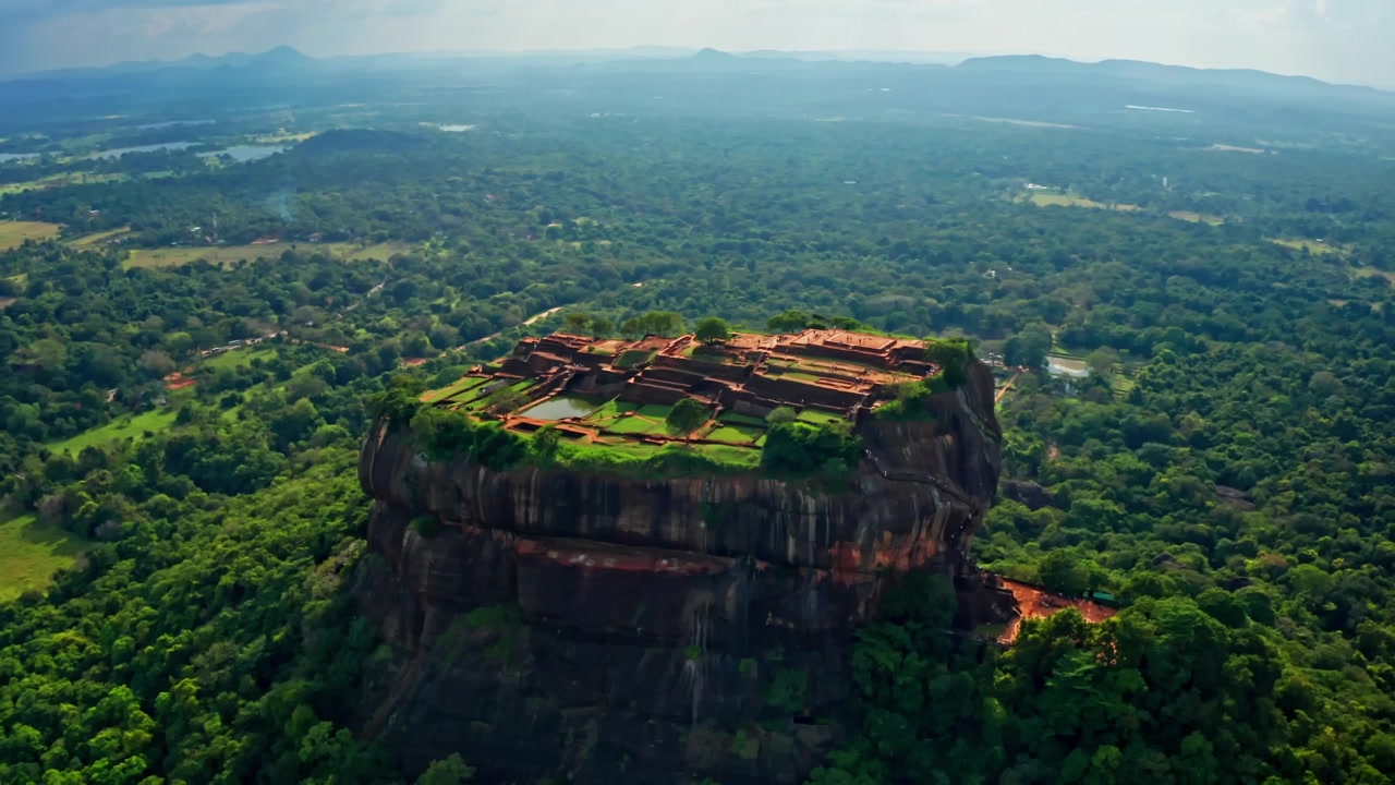 Vista aerea con drone di Sigiriya che mostra la sua iconica fortezza rocciosa circondata da una fitta giungla e vasti paesaggi tropicali in Sri Lanka