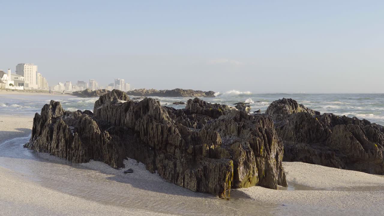 olas en la playa de blouberg y vista de rocas y rascacielos