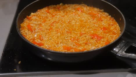 close-up shot of the rice cooking in a pan with vegetables on the stove serving hot