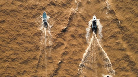 aerial top down of a group of yachts sailing on a brown color river at daytime