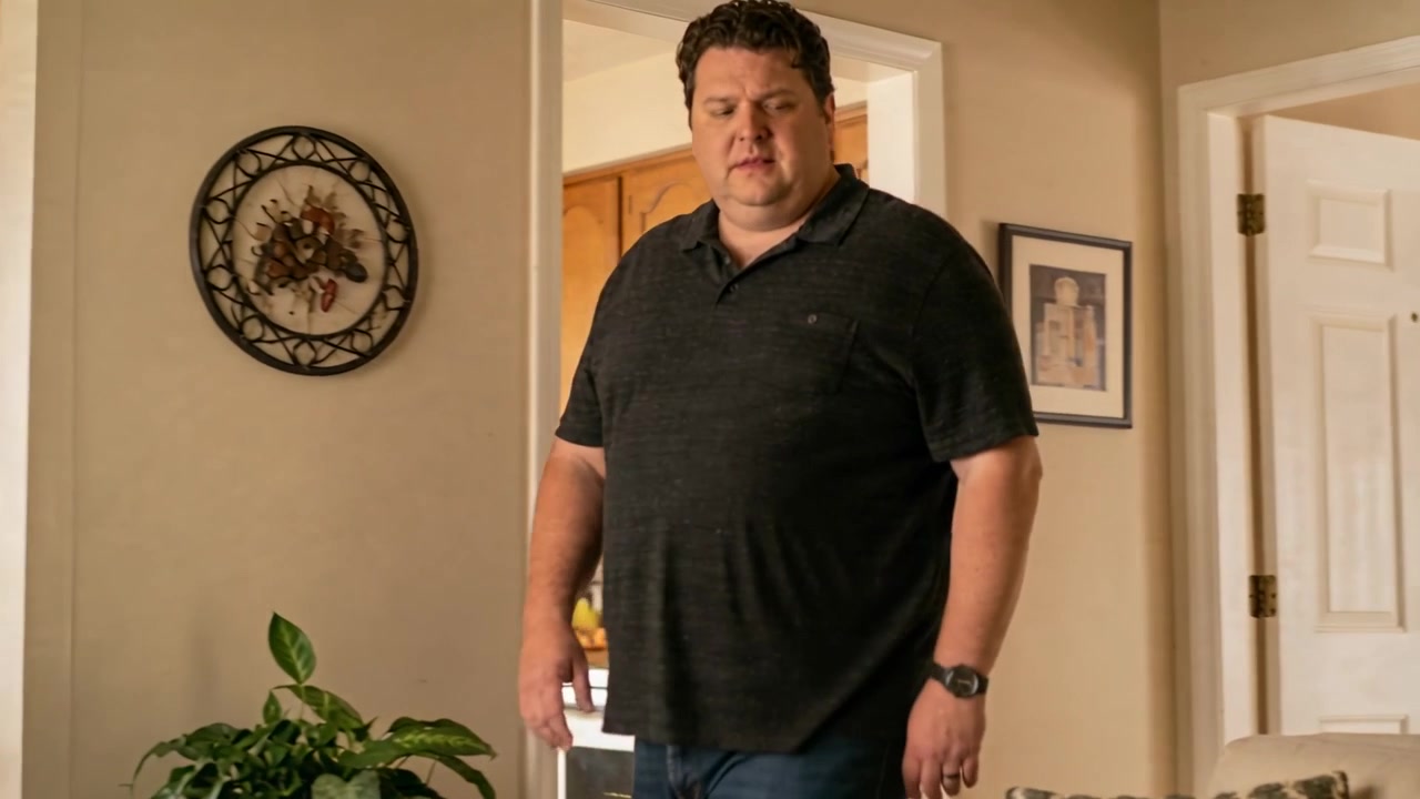 Døren åbner, hvilket får en mand i mørk polo og jeans til at gå ind i stuen og scanne sofaen.
