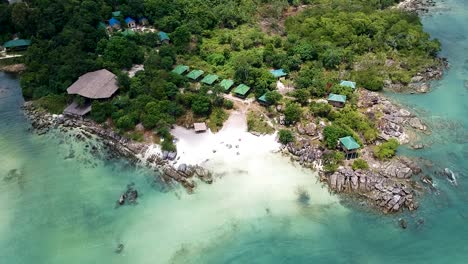 aerial reveal of a private island paradise beach resort with wooden beach huts in koh rong sanloem, cambodia