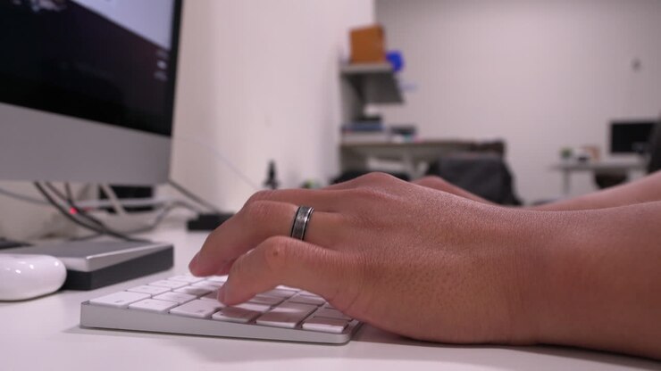 Married man's hands typing on keyboard in modern office