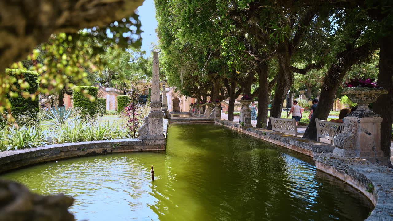 Vasca da giardino formale e obelisco al Museo Vizcaya di Miami. Vista prospettica di uno specchio d'acqua lungo e stretto e di un obelisco in pietra circondato da alberi ai Giardini Vizcaya di Miami.