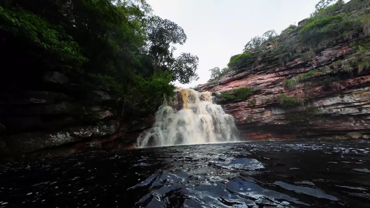 una cámara de acción extremadamente ancha nadando dentro del impresionante lago del pozo del diablo con una gran cascada en el hermoso parque nacional chapada diamantina en el noreste de brasil en un día nublado